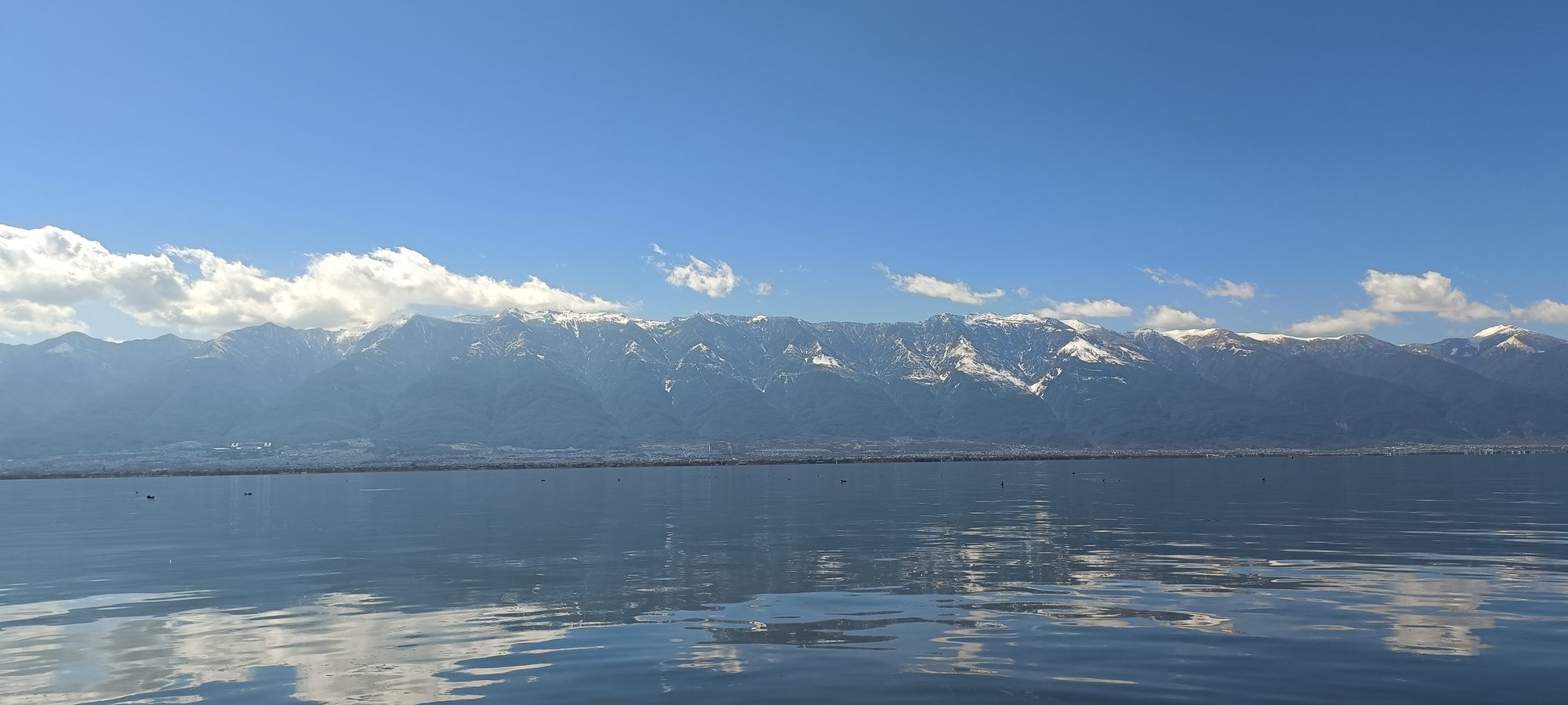 洱海与苍山同框：湖水倒映雪顶苍山，云朵低垂，湖岸线舒展